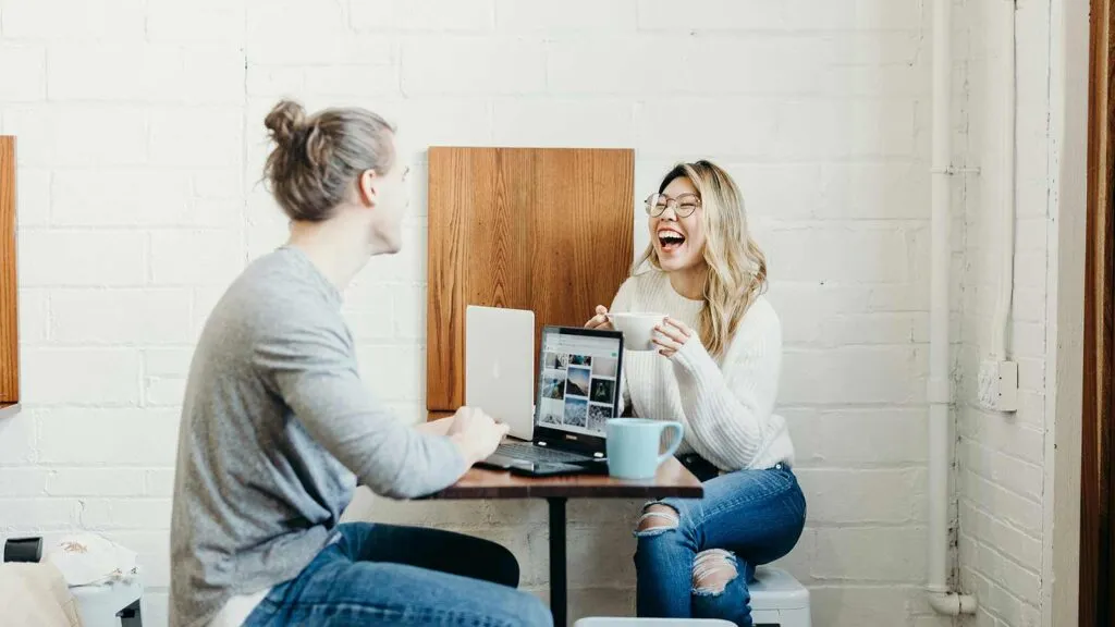 a woman laughing at a man sitting at a table with a laptop Nationwide AI Title Search