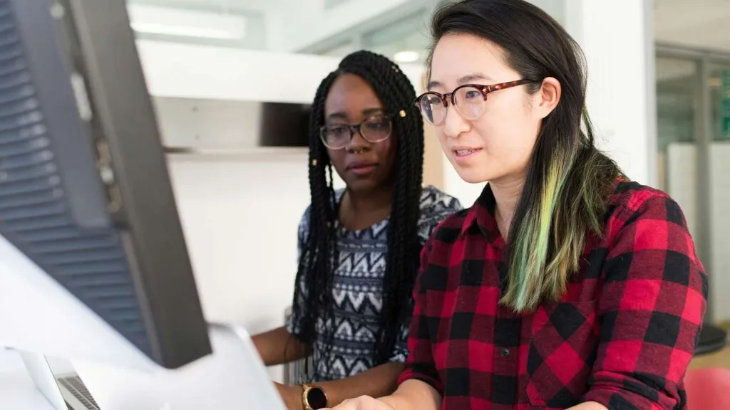 a group of women looking at a computer screen JSON