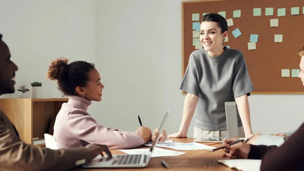 a woman standing in front of a group of people talking about same-day title updates